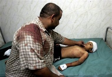 A father comforts his son who was wounded by a bomb attack on an American patrol in Baghdad today