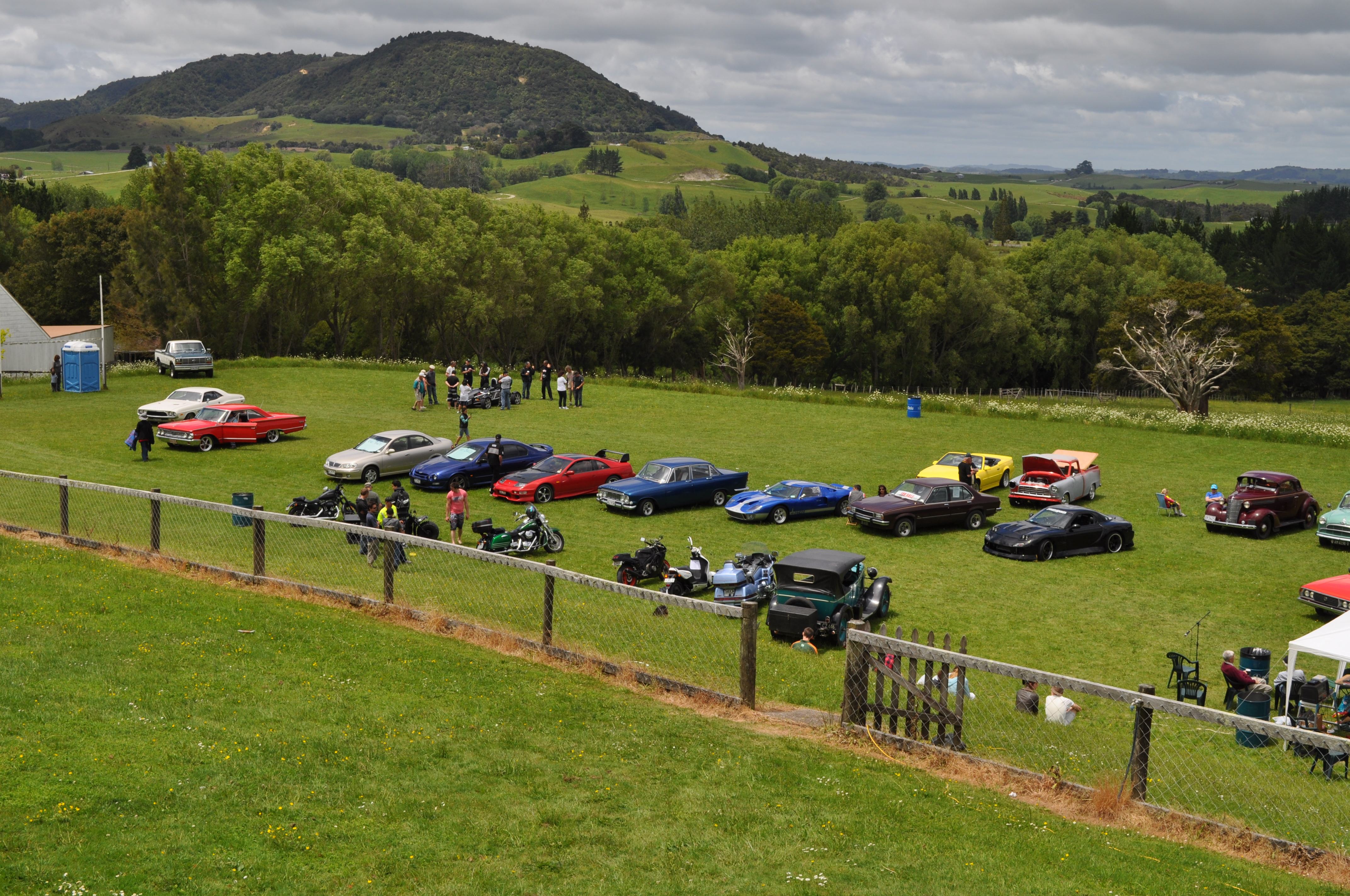 A group of people standing on top of a lush green field - Pistonheads