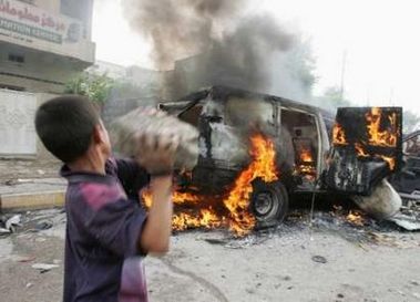 20061016_Basra boy throws a rock at a burning British consulate vehicle after RPG attack