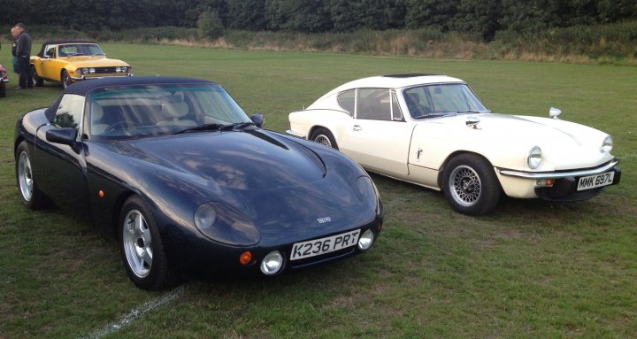 A white car parked in a field next to a car - Pistonheads