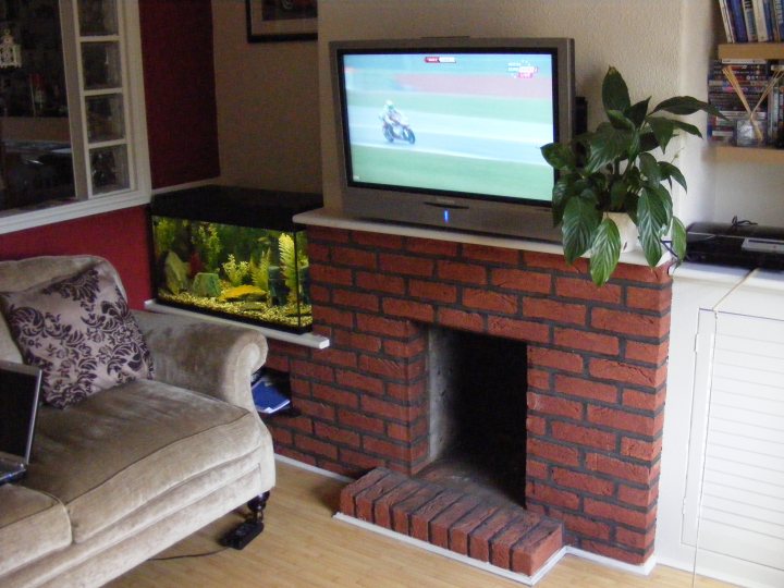 A living room with a fireplace and a tv - Pistonheads
