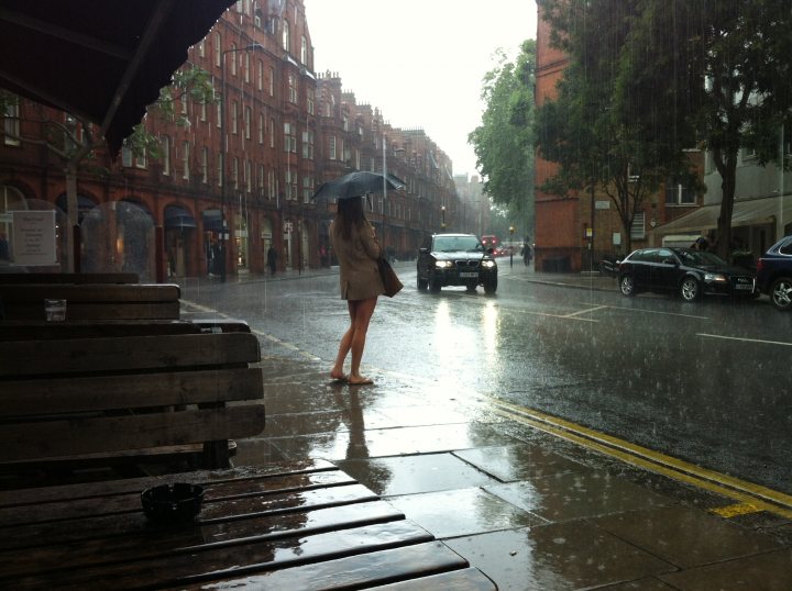 A woman walking down a street holding an umbrella - Pistonheads