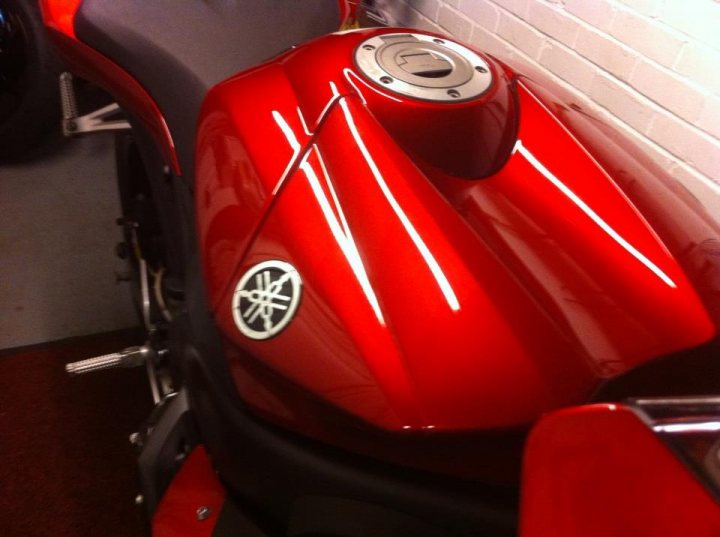 A red and black motorcycle is parked in a garage - Pistonheads