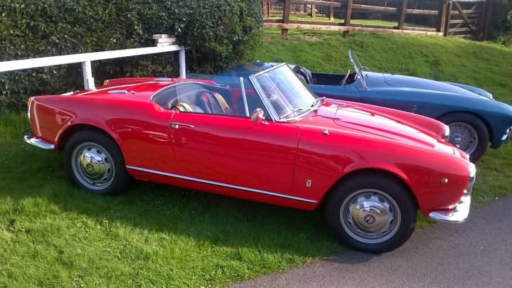 A vintage red car is parked in a field - Pistonheads