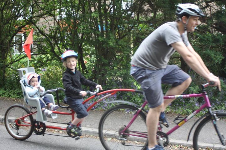 A man riding a bike down a street next to a woman - Pistonheads