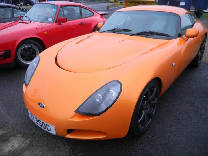 A red car is parked in a parking lot - Pistonheads