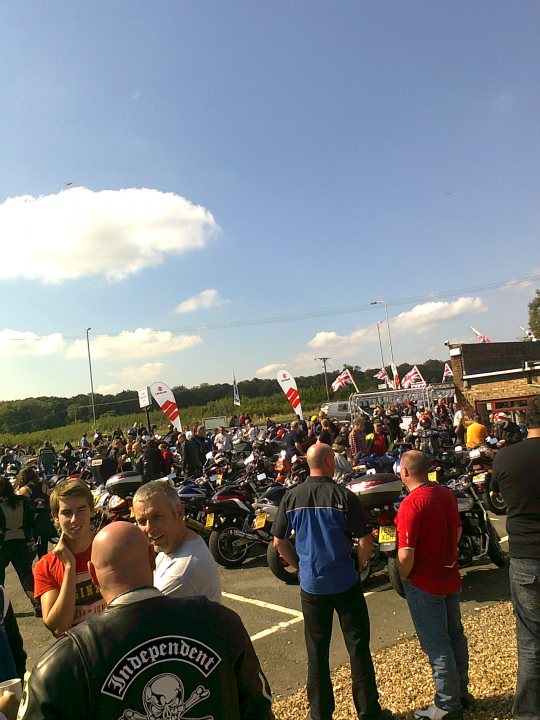 A crowd of people standing on top of a lush green field - Pistonheads