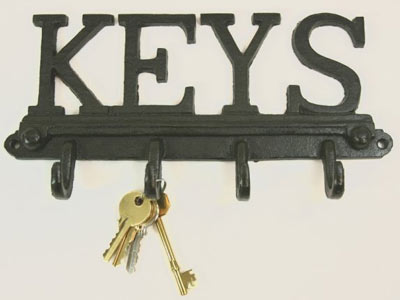 Pistonheads Thieves Protecting Home - The image showcases a monochrome black wall-mounted key rack. Prominently displayed on this rack are the keys themselves, which possess a polished metal look in shades of yellow and darker gold. The keys are arranged in no particular order, appearing slightly blurred, which gives them a somewhat three-dimensional effect against the solid black background. The letters "KEYS" are boldly inscribed above the magnetic key rack. This inscription forms an integral part of the design, creating a clear connection between the items and their function.