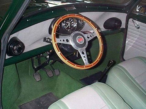 Best car dashboard - Page 16 - General Gassing - PistonHeads - The image shows the interior of a classic, bright green car. The car features white upholstery on the seats and is viewed from the driver's seat, looking towards the rear. The steering wheel is centrally located in front of the driver and two analog dials are visible on the dashboard, presumably representing the speedometer and tachometer. There is a black boot visible under the pedals, likely a protective cover for the engine. The overall look of the car suggests a vintage style.