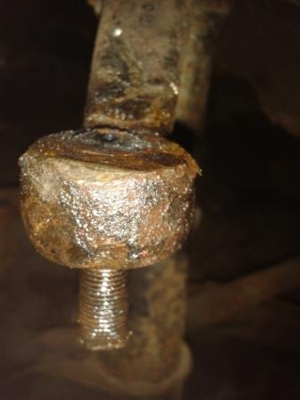 Siezed balljoint help - Page 1 - Home Mechanics - PistonHeads - The image shows a close-up of a rusty metal bracket with a peeling surface, possibly suffering from corrosion or wear. The metal appears dull and has debris attached to its sides. The bracket is tightly fastened into a structure, possibly a vehicle or a machine, with a visible bolt holding it in place. The focus of the image is on the bracket, which dominates the frame, while the surrounding environment is blurred, creating a shallow depth of field. The image appears to have a vintage or industrial aesthetic, suggesting long-term use and exposure to the elements.