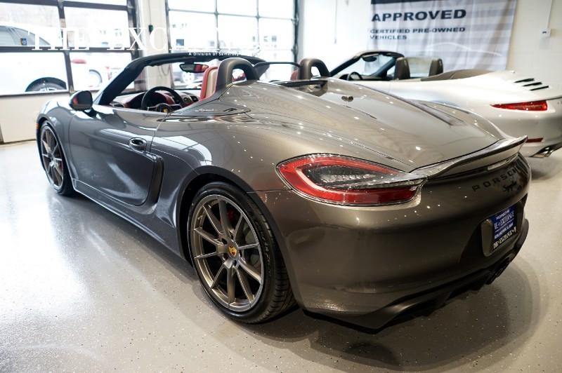 Boxster Spyder - Page 117 - Boxster/Cayman - PistonHeads - The image focuses on a striking gray sports car in a showroom setting. The car's logo and the wheel design suggest it's a convertible model from a well-known luxury car brand. The sports car emanates a sense of power and luxury, accentuated by the shiny exterior reflecting the overhead lights. The contrasting gray with the white floor and the other cars in the background creates a visually dynamic scene.