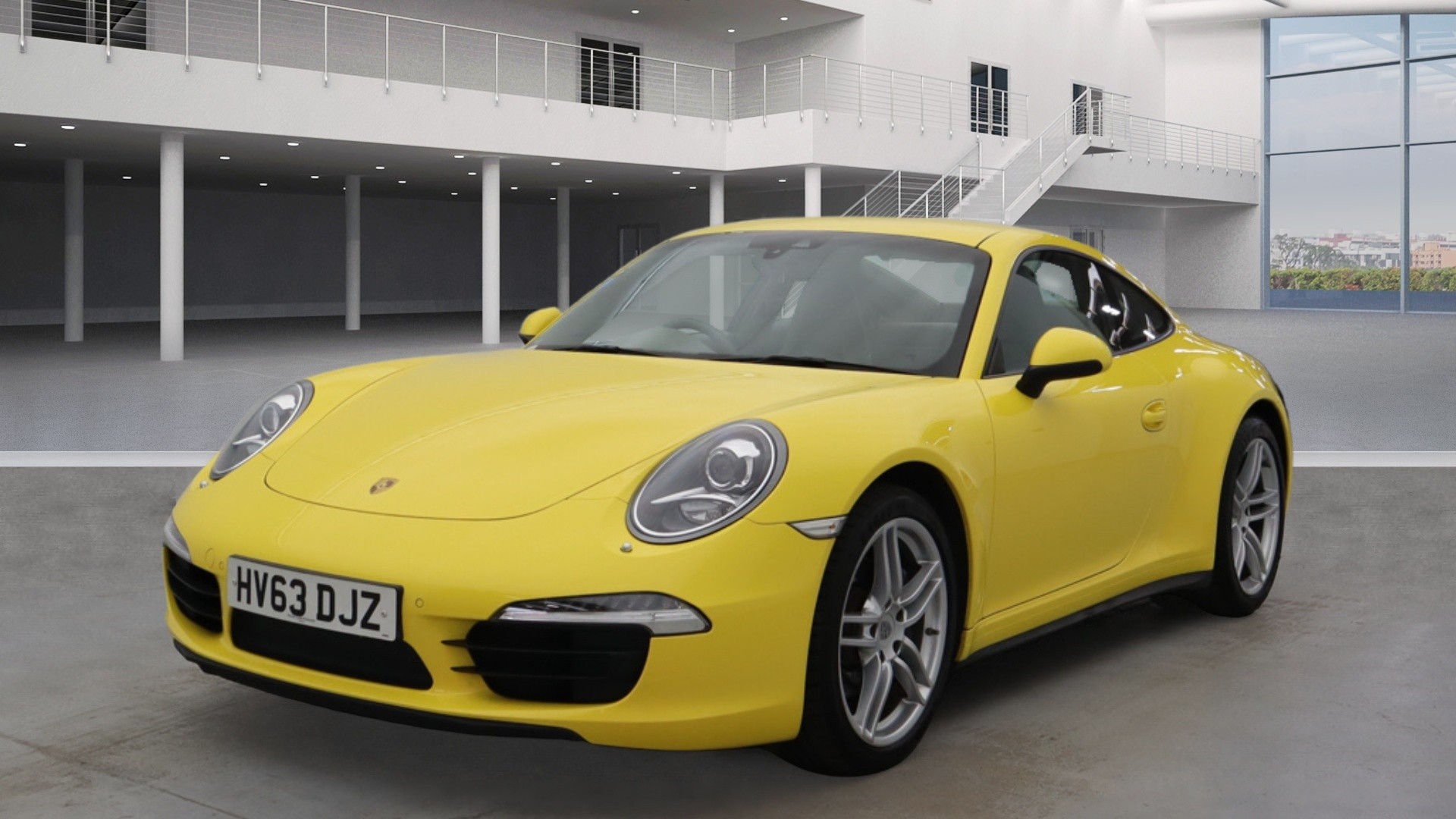 Best 911 for 1st time owner under 65k? - Page 3 - 911/Carrera GT - PistonHeads UK - The image is a studio photograph of a yellow Porsche sports car displayed indoors. It has a sleek design, with the vehicle's hood open, showcasing the engine. There are no visible texts or logos in the image. The background is minimalistic, featuring a gray floor and white walls that give the impression of a clean and spacious showroom or warehouse. The car is positioned on a smooth surface, likely to highlight its features and design.