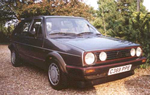 Pistonheads - The image shows a parked vintage black car with red stripes on its front on a gravel drive. The car has a distinctive front and rear design. The license plate indicates that the vehicle is from Great Britain, specifically Churchill, as suggested by the PPE letters. The scene is set in a natural environment under a tree-filled area, which suggests the car is possibly parked in a private property or a park-like environment.