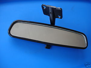 Fitting Rearview Mirror Pistonheads - The image comes across as a state object, specifically a rear view mirror base pulled away from its glass panel. The background is a plain blue piece of fabric or cardboard, which contrasts elegantly with the darker color of the mirror. The base itself has two clamp connectors, indicating that it would be attached to a part of a vehicle and then a mirror would snap into place. The overall image seems minimalistic, with the focus entirely on the object and its detail.