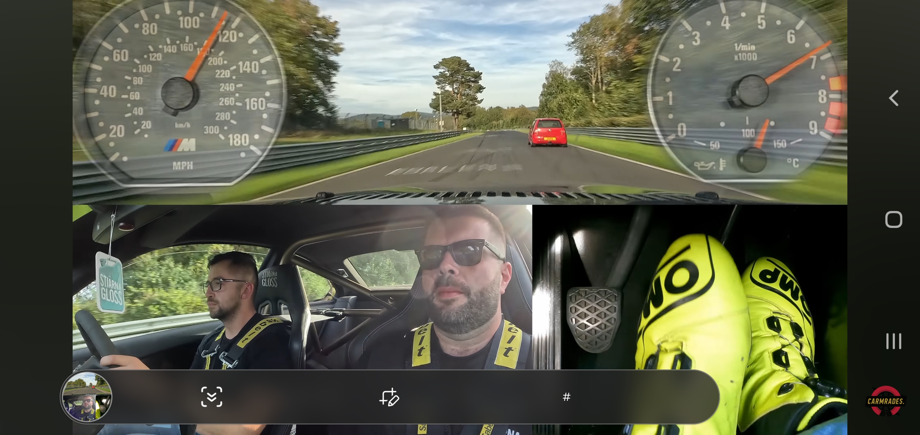 Lupo GTI - Page 27 - Readers' Cars - PistonHeads UK - The image is a screenshot of a smartphone displaying a video from the car's dashcam. In the center of the screen, there are two men driving in a vehicle. Both drivers are wearing helmets and appear to be engaged with their respective steering wheels. On the left side of the screen, we can see a dashboard with various gauges and indicators, including a speedometer. The right side of the screen displays a GPS navigation system interface, indicating that they are on the highway. In the foreground, there's a reflection of the driver on the left, showing his hands on the steering wheel, suggesting he is controlling the vehicle at the moment the photo was taken.