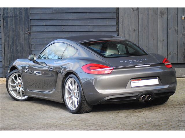 Well, the C63 is out, Cayman S is in.  - Page 1 - Boxster/Cayman - PistonHeads - The image shows a modern silver sports car parked on a surface with cobblestone-like paving. The car is parked facing towards the right side of the image, parallel to a wall behind it. It has a distinctive design with a long hood and coupe-style body, featuring alloy wheels, dual exhaust pipes, and a spoiler at the rear. The tail lights and side mirrors appear to be designed for optimized aerodynamics. The fronticance of the car and the use of silver suggest it's a high-end model with advanced technology features.