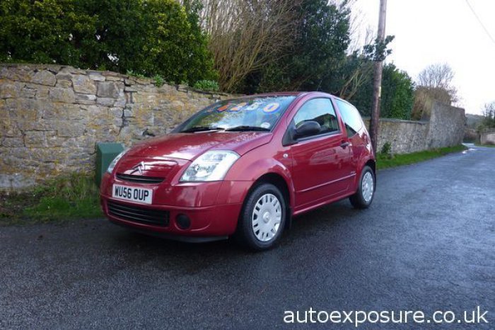 Seriously Overpriced Cars - Page 30 - General Gassing - PistonHeads - The image shows a red parked vehicle, specifically a hatchback car, situated in front of a stone wall. The vehicle appears well maintained and is sitting on a wet road, which suggests either recent rainfall or groundwater permeability. In the background, there's a blend of greenery and trees, contributing to a somewhat rural or semi-rural setting. Across the image, the watermark "autosexposure.co.uk" is visible, indicating that the photo is likely from an autosexposure service or company.