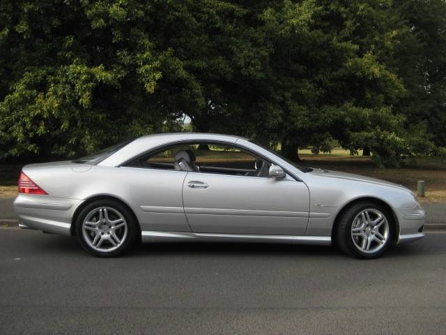 Pistonheads - The image portrays a gleaming silver sedan parked on a street. The car is positioned at a slight angle relative to the camera, allowing a clear view of its front and side. The vehicle features a sleek design with a notable curved side beam. The street on which the car is parked is lined with lush green trees, creating a peaceful and park-like setting. The image conveys a sense of tranquility and provides a view of the car's position in relation to the road and the surrounding environment.