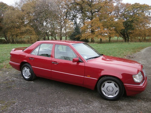 Pistonheads - The image features a vibrant red BMW parked on a gravel road. The car is sleek and well-maintained, with shiny exterior and matching black rims. It's positioned perpendicular to the camera, showcasing its front and side profile. Behind the car, there's a lush green field and a line of trees with autumn foliage, suggesting it might be the fall season. The overall atmosphere of the scene is peaceful and natural.