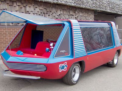 A 'period' classics pictures thread (Mk III) - Page 41 - Classic Cars and Yesterday's Heroes - PistonHeads UK - The image shows a unique vehicle that resembles the back of an old-fashioned car with a bright red and blue exterior. It appears to be a modified vehicle or a concept car, as it has an open top design. The car is parked indoors, possibly in a garage, with a brick wall in the background.