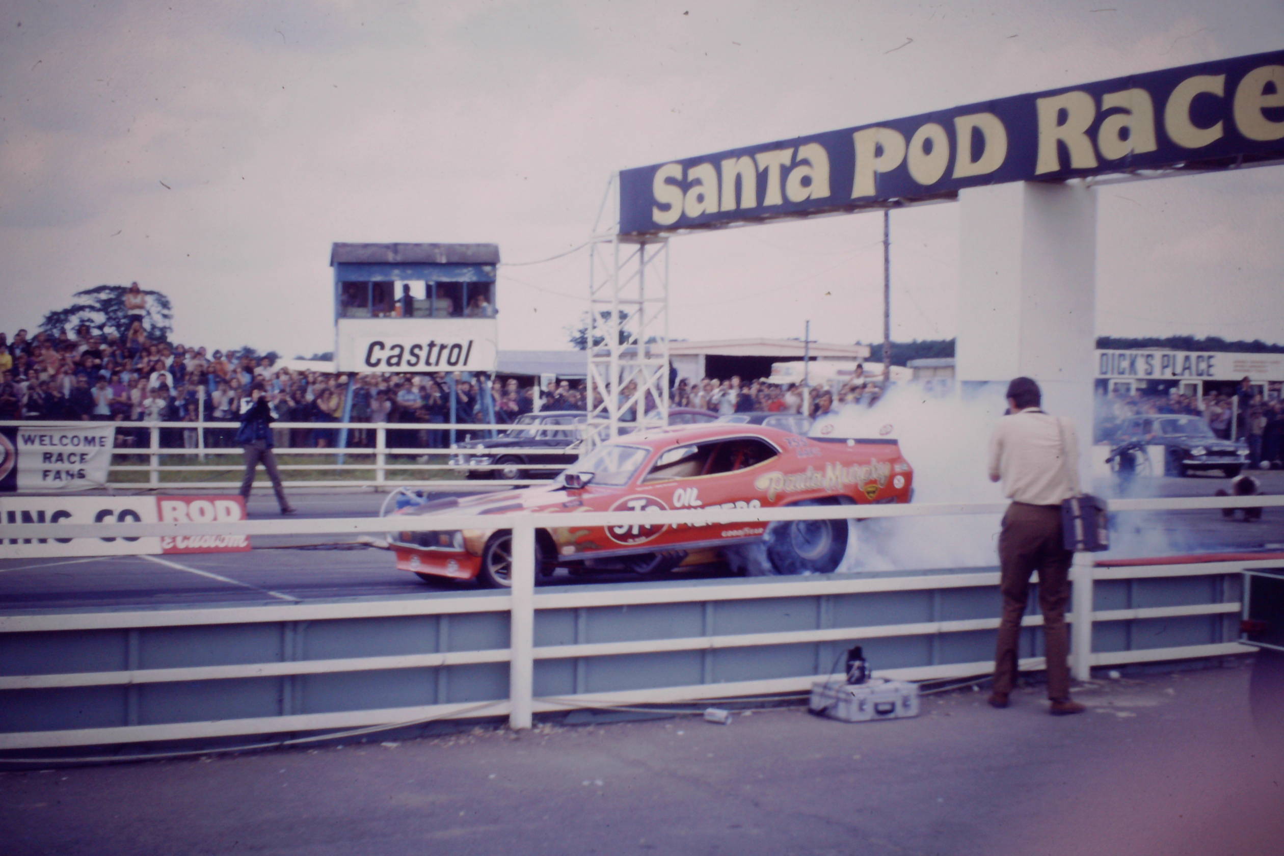 Fastest ladies always drive Mopars lol - Page 1 - Drag Racing - PistonHeads UK - The image captures a thrilling moment at a car race. A red racing car is the center of attention, captured in motion on the track. It's positioned under a sign that reads "Santa Pod Raceway," indicating the location of this exciting event. In the background, a crowd of spectators can be seen, their attention riveted on the ongoing race. The image also contains a text that reads "Castrol," likely related to a sponsorship or partnership at the raceway.