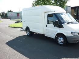 Transit Bodies Pistonheads - The image depicts a large white van parked on an asphalt surface in daylight. The van features a high roof, which contributes to its substantial size. Its body appears to be made of smooth, possibly tough, material, suitable for industrial or utility use. 

In the background, there are some buildings and what looks like a chain-link fence. The fence is made of metal, and the buildings are a mix of colors, with one predominantly red and another brown. The sky is clear, suggesting a bright and sunny day. The van appears to be alone in the lot, with no other vehicles or pedestrians visible in the immediate vicinity. 

The van's tilted windows and wide doors give it a utilitarian look, suggesting its capacity to carry various types of cargo or equipment. The image does not contain any text or other distinguishing marks that would provide additional context about the van's specific use or origin. 

Overall, the image presents a straightforward view of a large white van in a parking lot, with no explicit action taking place.