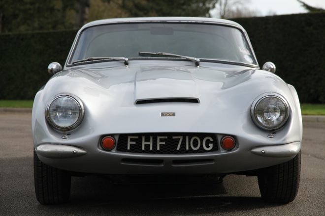 Early TVR Pictures - Page 35 - Classics - PistonHeads - The image captures a classic silver Porsche, parked on a gray asphalt surface. The car is a convertible, with a distinctive front drum brakes glow red, adding a touch of antiquation to its aerodynamic design. The registration on the front reads "FH 710G," indicating the car's license plate. The backdrop features a neatly trimmed hedge, suggesting the vehicle is parked in a well-maintained lot or a gated community.