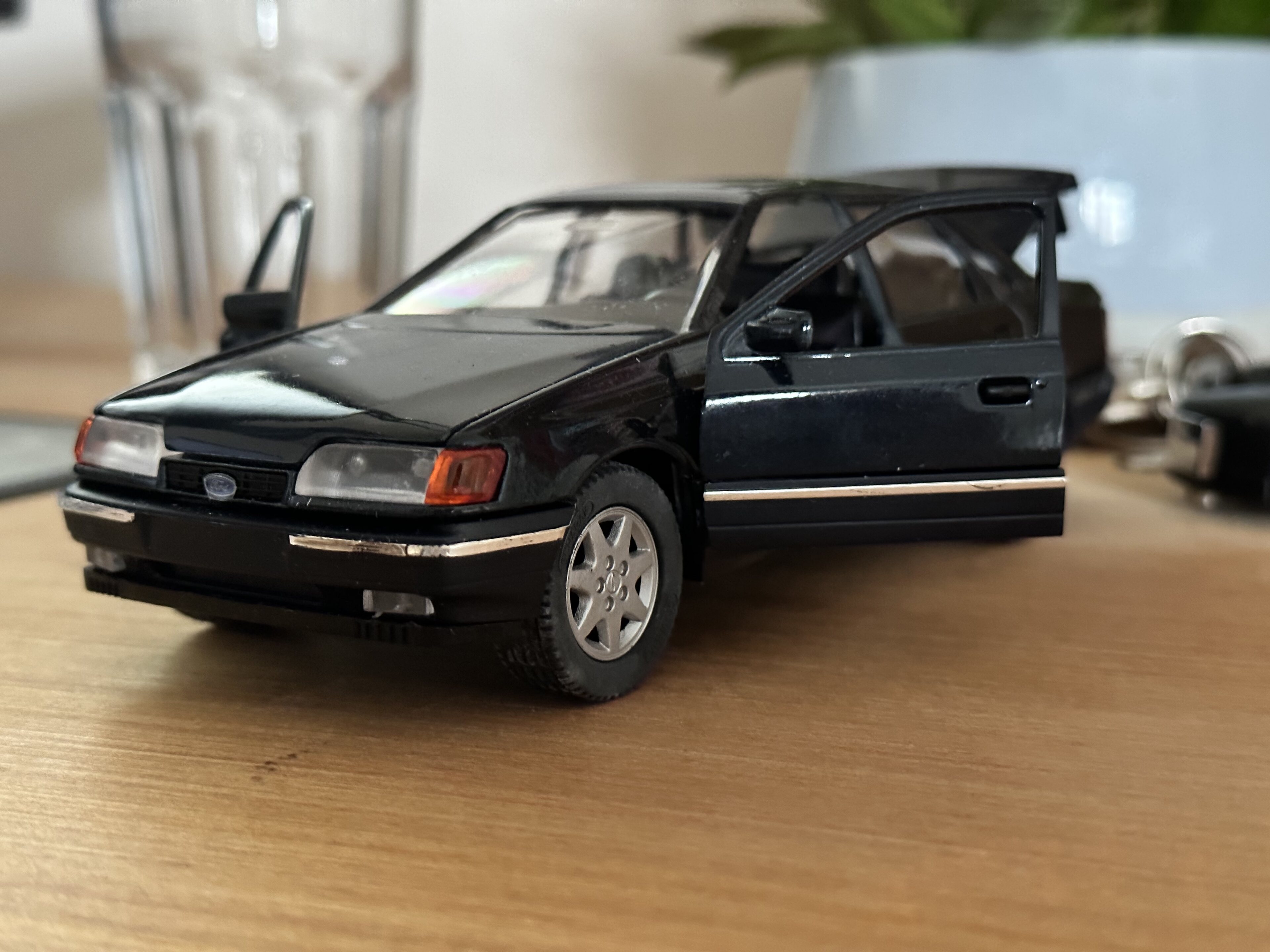 Ford Granada - Attainable 90s Interesting Ford - Page 1 - Readers' Cars - PistonHeads UK - The image showcases a black toy car, which is a replica of a Ford Escort. It appears to be a collectible item, possibly part of an automobile collection or a hobby for the owner. The car is positioned on a surface that could be a table or a countertop, and there's a key placed in its ignition. In the background, there seems to be a white wall and some other objects, but they are not clearly distinguishable.