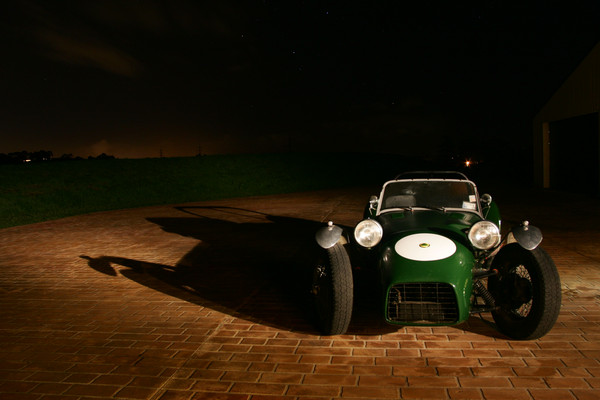 A motorcycle is parked in a parking lot - Pistonheads - The image showcases a classic green Morgan car parked on a brick driveway at night. The old-fashioned roadster's hood is open, revealing its engine compartment. The vehicle's shape and size are prominent in the frame, with its body reflecting the light. The surrounding darkness contrasts with the car's vibrant green color, emphasizing its vintage design.