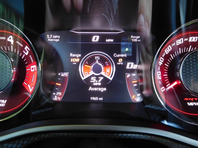 Hellcat good mpg...and not so good - Page 1 - Yank Motors - PistonHeads - The image showcases a car's digital instrument cluster displaying a variety of readings. It indicates a speedometer reading of 5.7 miles per gallon (MPG) Average, a brake range of '0 50', '0 60', and '0 80', a 5,700 RPM (Revolutions Per Minute), a SECONDS timer showing 75 seconds, and a DIGITIAL READOUT with various readings including 108K Miles, 40 degrees (likely ambient temperature), 128 news outlets (a location-based reading unusual for an instrument cluster), 158 charge cycles (suggesting batter life), and a year of '1955'. The values are set against a red and black background, typical of a car's dashboard.