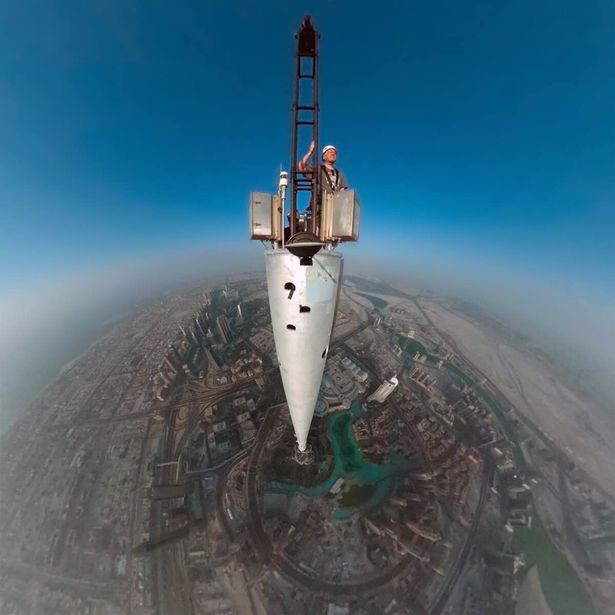 The camera can capture some fantastic moments IV - Page 376 - Photography & Video - PistonHeads - The image captures a man standing on top of a water tower. He faces the camera, appearing calm and composed. The tower is predominantly white with black markings. It's a clear day with a brilliant blue sky and the faint outlines of city structures visible in the distance. The man is dressed appropriately for the weather and seems to be at ease amidst the structures below. The perspective of the image looks directly beneath the water tower, providing a unique viewpoint.