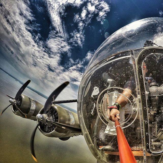 Post amazingly cool pictures of aircraft (Volume 2) - Page 422 - Boats, Planes & Trains - PistonHeads - The image captures a unique perspective inside an old airplane's cockpit. From the pilot's seat, you can see a serene view of the ocean and the vast sky dotted with white clouds. One of the most striking features in the cockpit is a large bubble, presumably for enhanced visibility. Adding an interesting layer to the image, a person with a red and white striped pole or tool can be seen, peering through the cockpit window. It seems to be a day of inspection or a special flight, given the presence of this individual.