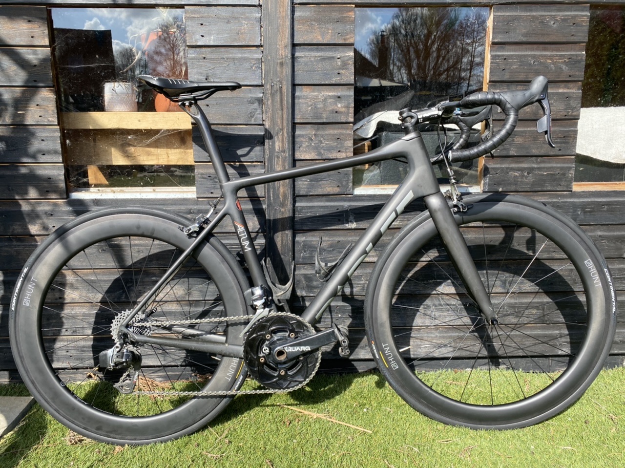 The "Show off your bike" thread! (Vol 2) - Page 87 - Pedal Powered - PistonHeads UK - The image shows a sleek, black bicycle leaning against a wooden structure. The bike is equipped with two wheels and features multiple gears. It is positioned outdoors in an environment that suggests it might be a garage or storage area. There are no people visible in the scene.