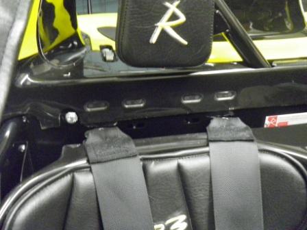 Mounts Harness Pistonheads - The image shows a close-up view of a vehicle's internal backrest storage compartment, likely from the driver's side. A package has been placed on the top of the compartment and a car seat, labeled "R8," is visible beneath it. Although partially obscured by the packaging, the Spinis brand is also apparent in the storage compartment. The storage compartment appears to be secured by black straps for added safety.