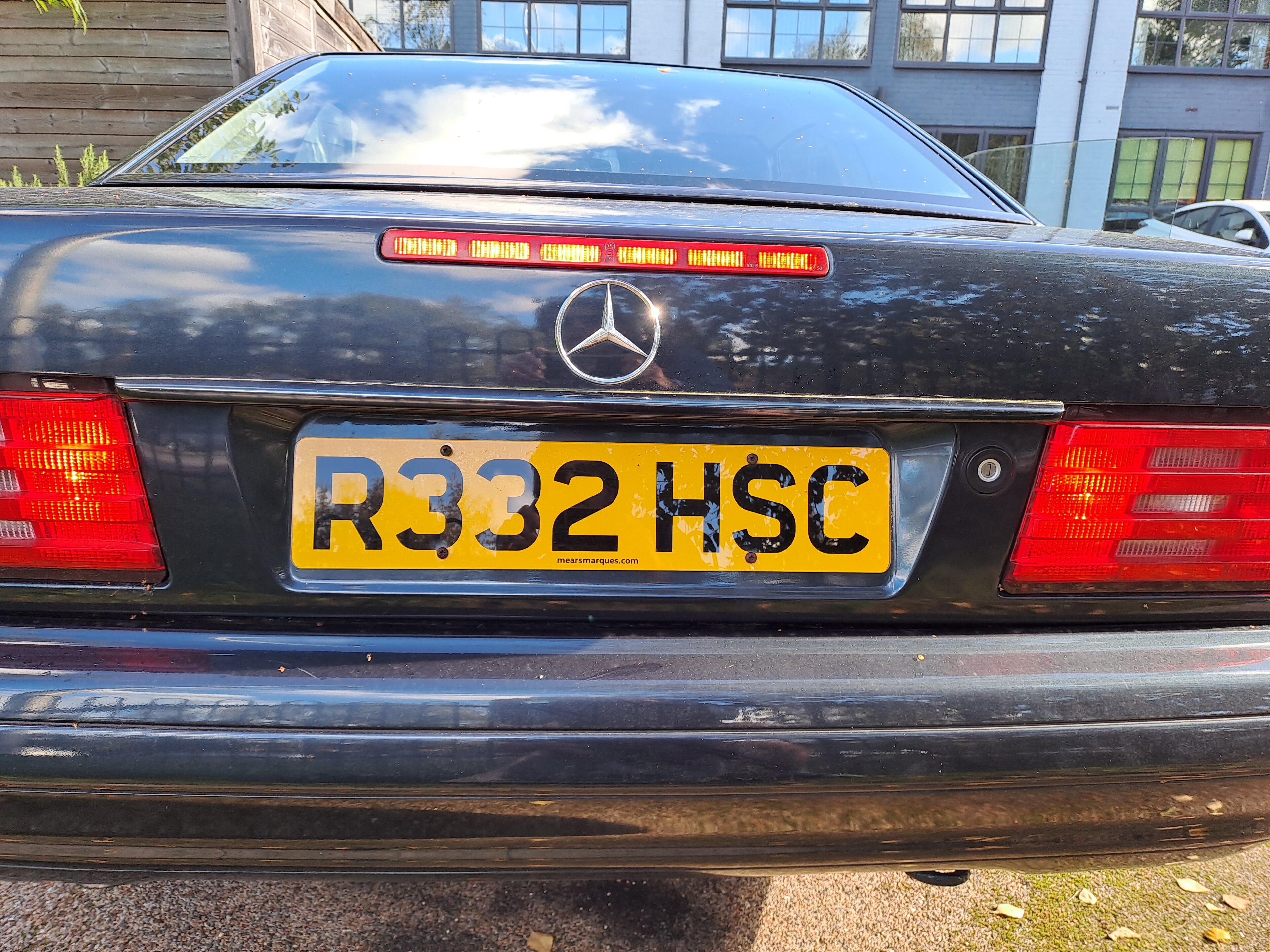 Pistonheads - The image shows a black Mercedes-Benz car parked outdoors. It has a distinctive license plate that reads "R532 HSC". The car appears to be a coupe or saloon model, and it's positioned facing the viewer, with the left side visible in the photo. There is no other vehicle in sight, suggesting it might be alone at the moment. The setting seems to be a street or parking area as there are blurred elements in the background that indicate an urban environment.