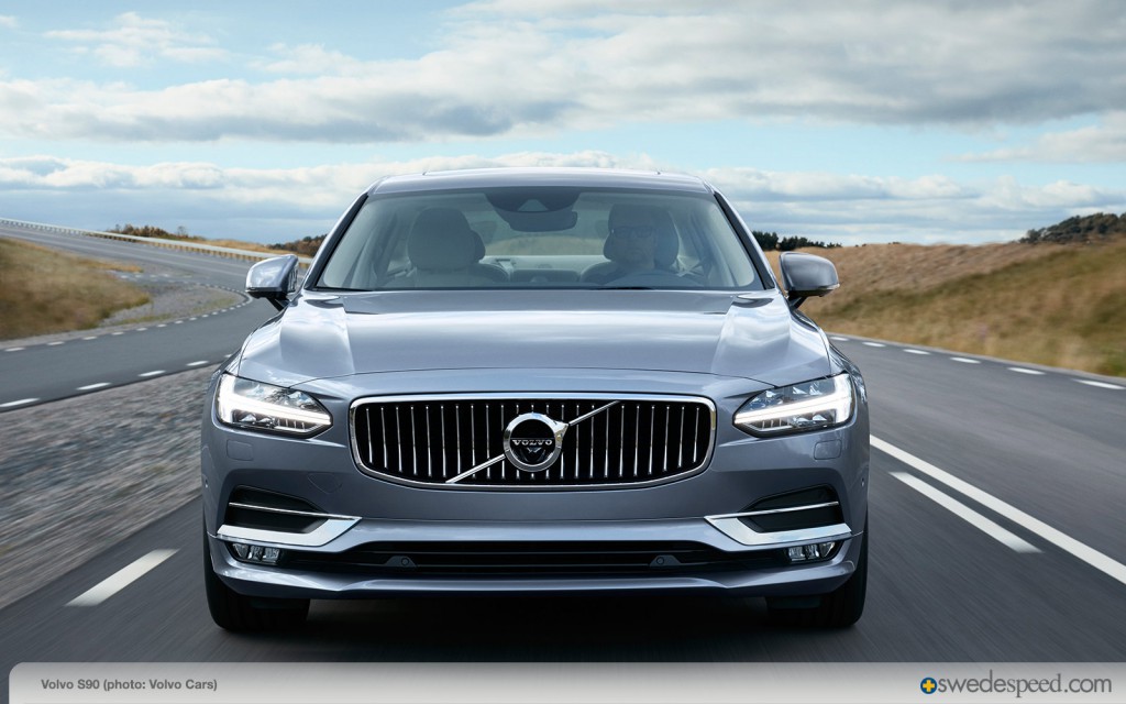 A car is parked on the side of the road - Pistonheads - The image shows a modern, silver-colored vehicle, which appears to be a Volvo, driving on a road with two white dividers. The rear of the car is prominently featured, displaying the iconic Volvo grille. Outside the vehicle, the sky is overcast with large, fluffy clouds, and behind it, the landscape includes rolling hills and vegetation. The photo is taken during the day under natural light, and the presence of a watermark across the image suggests it is a professional or promotional photograph, possibly for an advertising campaign. The vehicle is in motion along a curving road, suggesting speed and motion.