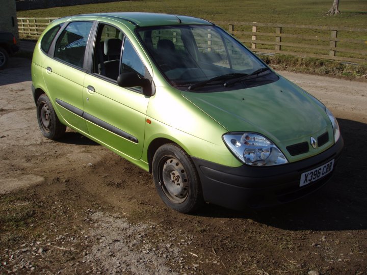 The first car before and after - Page 1 - Readers' Cars - PistonHeads - The image features a bright green hatchback car sitting on a gravel driveway. The vehicle's design includes a prominent front bumper and grill, and the wheels are black and look to be both new and shiny. The car has a closed window in the driver's seat, suggesting it is parked. Behind the car, there's a fence and a grassy area, indicating that this might be someone's private property or a driveway to a residence or business. The angle of the photo provides a clear view of the car and its immediate surroundings.