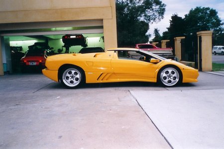 Show us your Diablo  - Page 6 - Diablo/Murcielago/Aventador - PistonHeads - The image features a vibrant yellow sports car parked in a garage bay. The car is sleek and polished, showcasing a shiny exterior that stands out in the well-lit environment. A red sports car can be seen parked next to it, suggesting that this might be a specialized garage for exotic vehicles. The garage is mostly empty and well-maintained, with a car lift visible in the background. The overall atmosphere suggests a place dedicated to the maintenance and display of high-performance cars.