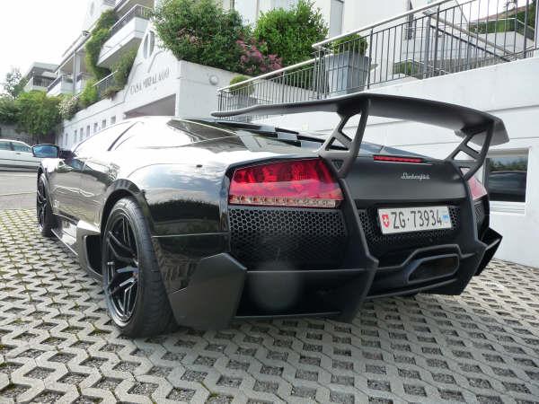 Italian Speeding Pistonheads Fines - The image showcases the rear end of a black sports car parked on a paved area. The car's license plate reads "ZG-733". The design includes a rear wing, two exhaust pipes, and a spoiler, elements typical of high-performance vehicles. For safety, the car is equipped with a parking brake, which can be seen when the image is viewed from an angle above the car. The vehicle's sleek lines and glossy finish indicate it's well-maintained and could be a luxury model or a high-end sports car.