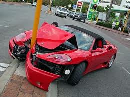 Please do not bump any old posts! - Page 1 - Vipers - PistonHeads - The image shows a red car that has been involved in a head-on collision with another car, resulting in serious damage to both vehicles. The car's hood and front-end are visibly crushed and deformed due to the impact. There are a few people present in the background, observing the scene. The cars are on the roadside, close to each other, likely just having occurred. The setting appears to be an urban or suburban area.