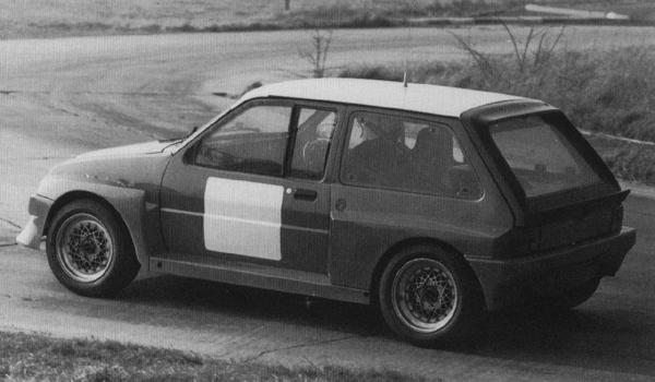 Pistonheads Scale Metro - The image is a black and white photograph of a small, hatchback car that appears to be vintage in style. The car is predominantly gray with a panel of white on the lower side and above the rear wheel, resembling a traditional racing livery. It features a crouched windscreen, recessed rear wheel arches, and a short rear spoiler. The wheels are a distinctive five-spoke design. The photograph seems to be taken during the day on a clear day, as evidenced by the lack of shadows. There are no visible texts or distinguishing marks on the car that indicate specific make or model.