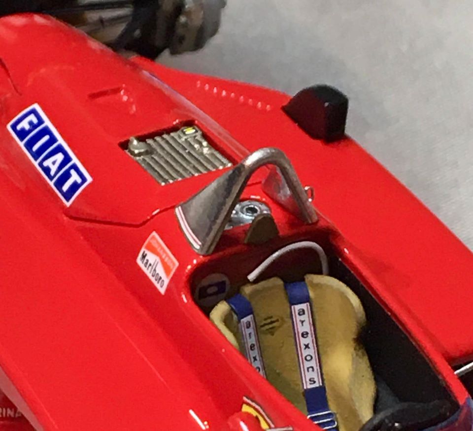 A bag of luggage sitting on top of a wooden floor - Pistonheads - The image shows a classic red Ferrari F1 car, which is a toy replica. The car is displayed on a table, with its hood open revealing the engine and other internal components. There's a sign attached to the car that says "Ferrari," indicating the make of the vehicle. Additionally, there are two yellow gloves placed near the car, perhaps for handling or driving purposes. The background is neutral, putting the focus entirely on the toy Ferrari model.