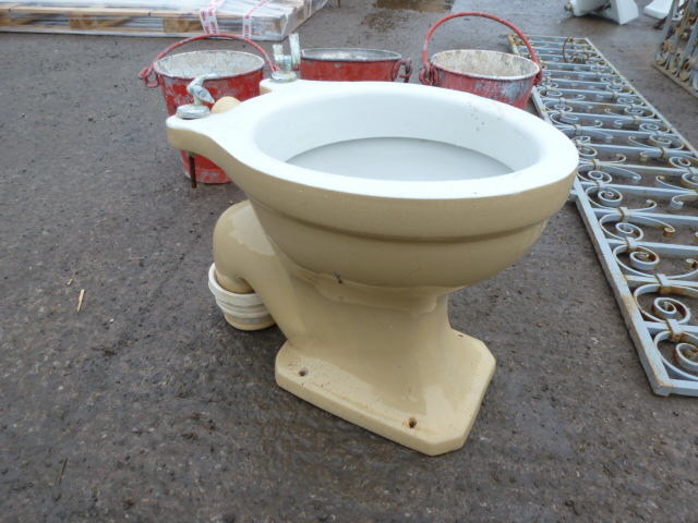 A white toilet sitting in the middle of a street - Pistonheads - The image shows a rustic setting with a large toilet set on the ground. Surrounding the toilet, there are several cans or buckets. The ground appears to be unpaved, possibly suggesting an outdoor or construction environment. In the background, there is a collection of indistinct objects, which might be part of the same discarded items. The toilet is positioned in a way that shows its sides, and it has an area with pipes visible underneath its tank. The environment is outdoors and dirty, giving the scene an overall rustic or industrial appearance.