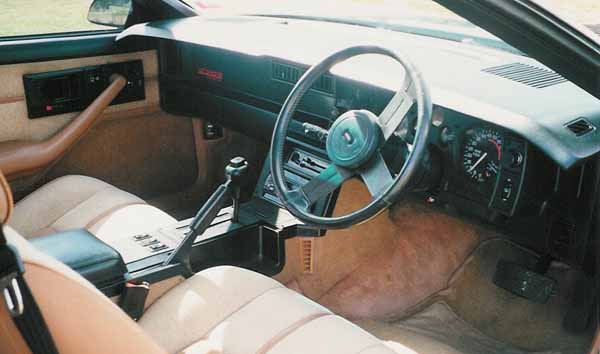 Pistonheads Chevrolet Iroc Camaro Tavs Big - The image shows the interior of a classic car with a wooden dashboard. The image is taken from the perspective of the passenger's seat, with focus on the steering wheel. The steering wheel is leather-wrapped, and the dashboard has a mix of gauges and other controls. The upholstery is beige, and the shifter knob visible in the dashboard suggests it's a manual transmission. The overall image exudes a sense of vintage charm.