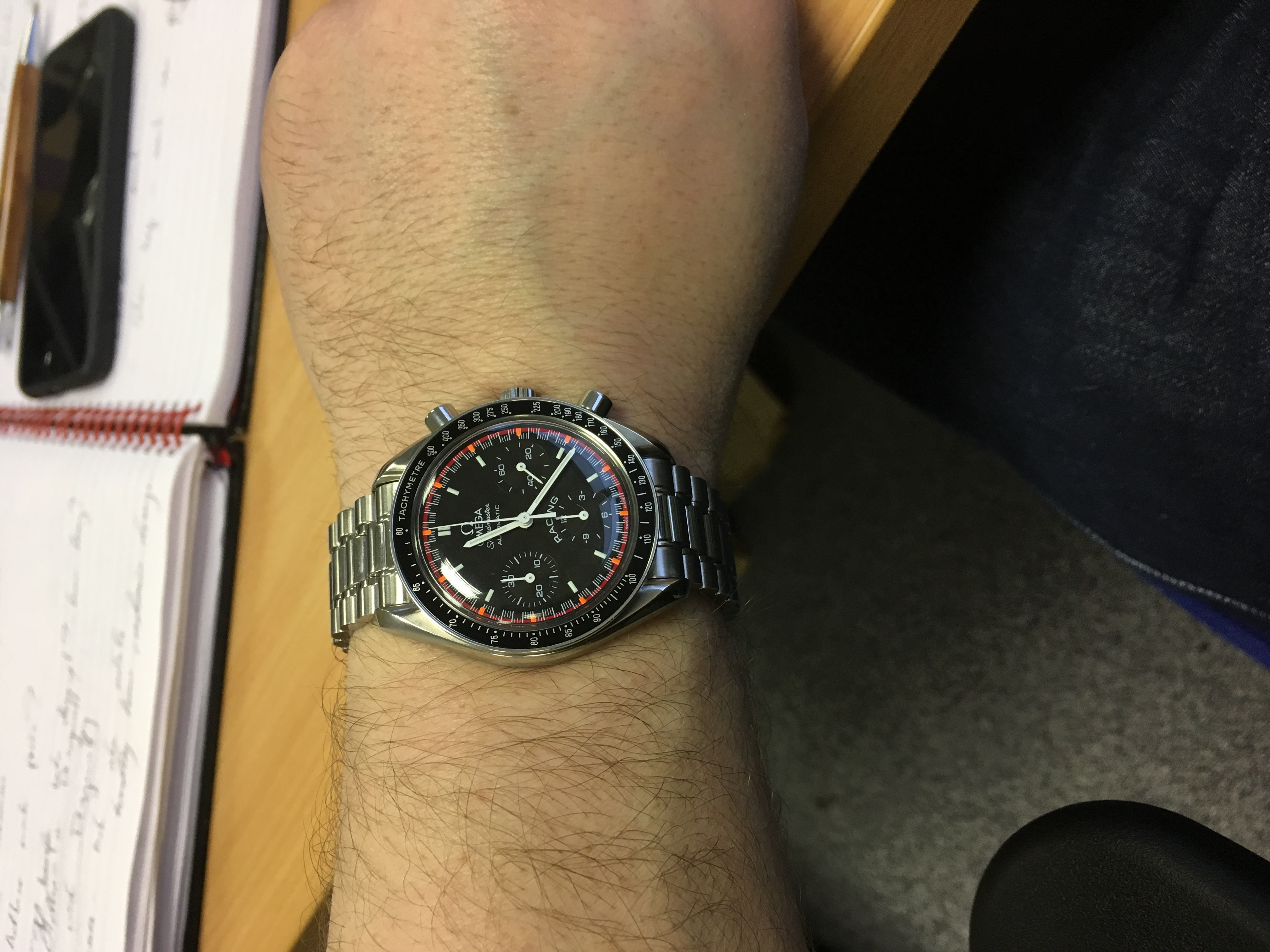 Wrist Check 2017 - Page 4 - Watches - PistonHeads - A person's hand with a black wristwatch. The watch has a silver band and a white face with orange and red details. The watch also has three smaller dials. The hand is resting on a desk which holds a book and other documents. The focus of the image is on the hand and wristwatch.