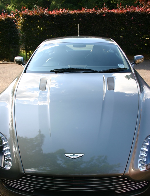 Ready Detailed Pistonheads Sold - The image showcases a silver, sleek sports car with a distinctive design. The car features a chrome grill, accentuating its luxurious appearance, and is further characterized by its silver finish. The vehicle is parked on a driveway, adjacent to a fence with a well-manicured hedge in the background, suggesting a well-maintained or upper-class residential area. The ground appears to be paved, and there is a hint of natural darkness in the corner, likely indicating a shadow.