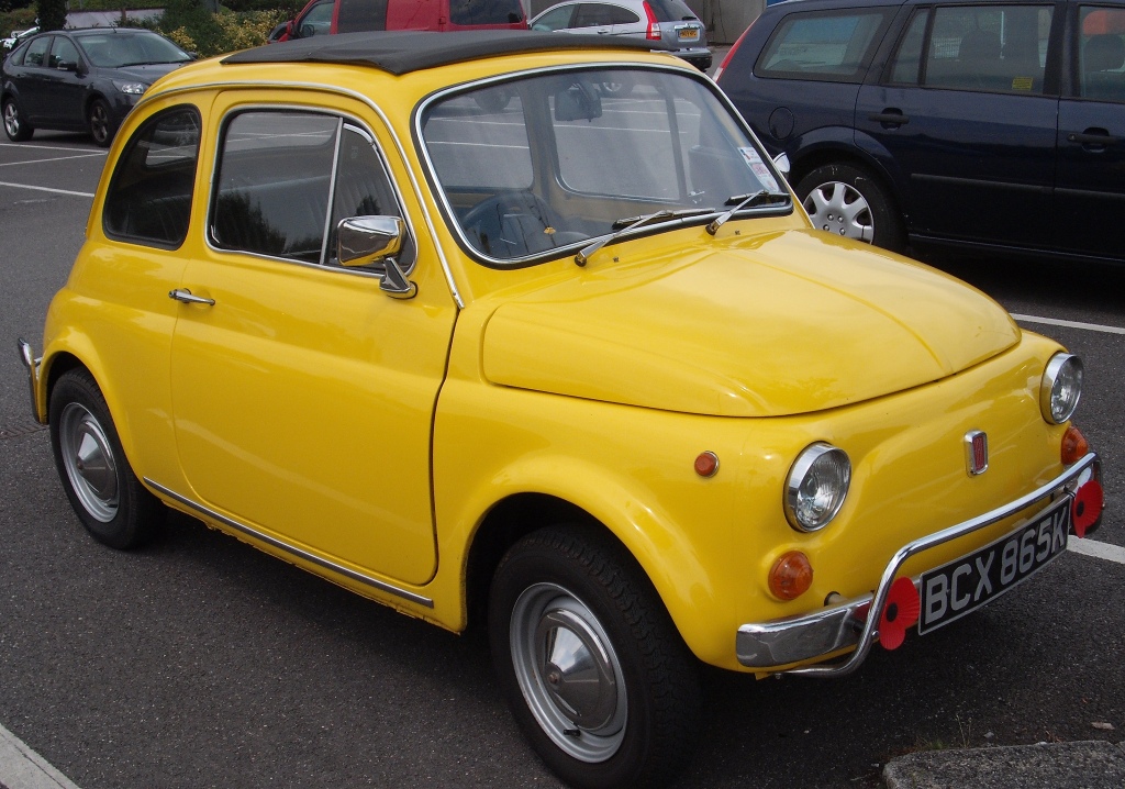 COOL CLASSIC CAR SPOTTERS POST!!! Vol 2 - Page 71 - Classic Cars and Yesterday's Heroes - PistonHeads - This image features a vibrant, yellow Fiat 500 in a parking lot. The Fiat, characterized by its iconic round front, is positioned in the foreground with a distinct black roof and white license plate. In the background, other parked cars are visible, creating a contrast of colors and shapes. The contrast of the Fiat's bright color against the subtle hues of the other vehicles adds a pop of color to the scene.