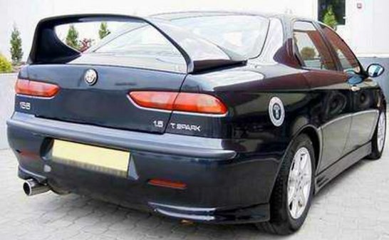 RE: Spoiler alert: PH Blog - Page 7 - General Gassing - PistonHeads - This image features a black, two-door coupe parked outdoors. The car is viewed from a rear-three-quarter angle, revealing the design elements of the vehicle, such as the high boot line, taillights, and a rear spoiler. The reflective surface of the car suggests a shiny finish, and an emblem resembling a flower or emblem is visible on the trunk lid. The exhaust pipes of the car are also noticeable. The environment is somewhat nondescript, with a gray-toned ground and a building in the background. There are no visible texts or numbers that provide specific identification or information about the car.