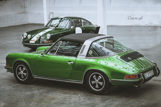 A few pictures I quite like - please add to it ...... - Page 6 - Porsche General - PistonHeads - The image presents a step-back-in-time view during a car show, showcasing two classic Porsche sports cars. The first car on the right is a vibrant green with a white stripe, reminiscent of classic racing cars from the 1960s or 1970s. Adjacent to this, on the left, is a glossy black vintage car, its sleek design contrasting with the green Porsche. Both cars are parked side by side in front of a wall adorned with abstract patterns. The setting suggests a luxury motorsport event, with the cars on display for visitors to admire.