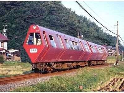 A red train traveling down train tracks next to a forest